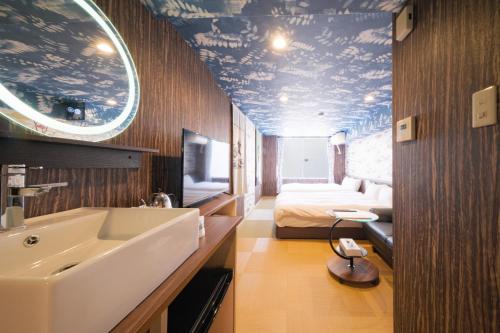 a bathroom with a sink and a bed in a room at 泊るHouse千葉駅1分 J - 東京ディズニーランドまで30分 線路傍騒音あり in Chiba