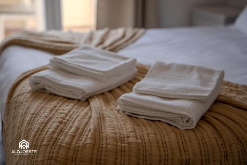two white towels sitting on top of a bed at Seaside Santa Cruz- Beachfront Apt 3 BDR with BBQ in Silveira