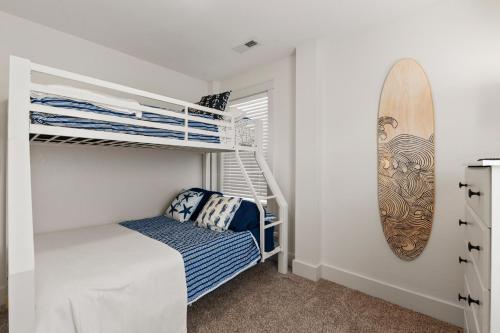 a bedroom with bunk beds and a surfboard on the wall at Work Trip in Kill Devil Hills