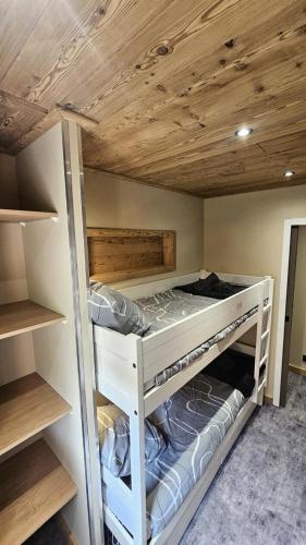 Ce lit superposé blanc se trouve dans un dortoir doté de plafonds en bois. dans l'établissement Résidence Le Thabor - maeva Home - Appartement 2 pièces 6 personnes - Sélection MAE-2784, à Le Désert