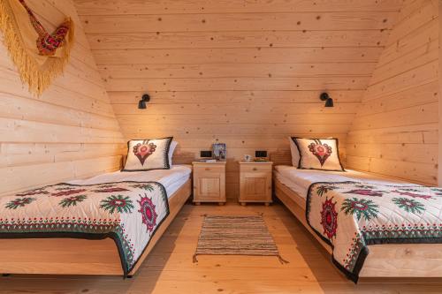 two beds in a log cabin bedroom with wooden walls at Góralskie Domki u Topora in Czarny Dunajec