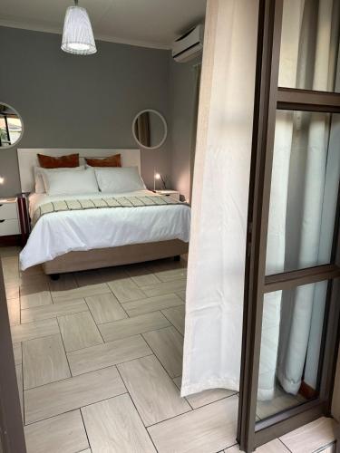 a bedroom with a bed and a wooden floor at Exquisite Home & Living in Matsapha