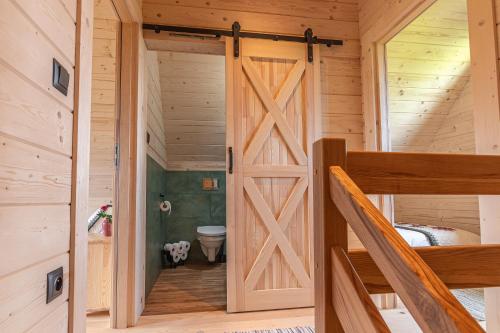a wooden door in a room with a bed and a toilet at Góralskie Domki u Topora in Czarny Dunajec