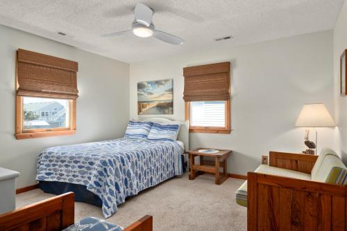 a bedroom with a bed with a blue comforter and two windows at Y-Worry in Kill Devil Hills
