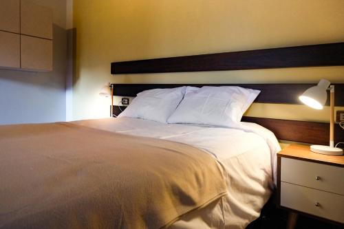 a bedroom with a large white bed with a wooden headboard at Ayra Hotel Boutique in Pisac