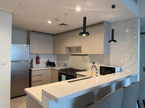 a kitchen with white cabinets and a stove top oven at Dubai Frame Views Steps from Metro & Sheikh Zayed Road in Dubai