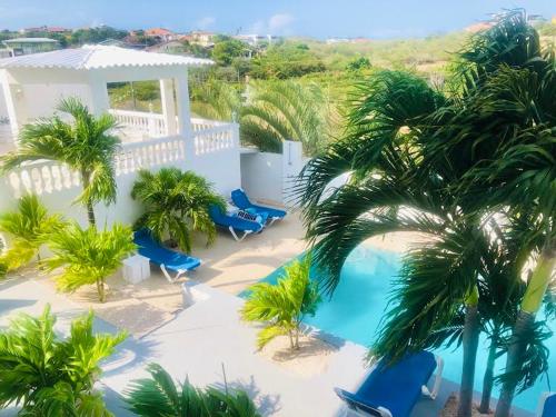 an aerial view of a resort with a pool and palm trees at Group Accommodation Jan Thiel Curaçao in Willemstad