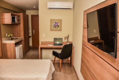a room with a bed and a desk with a laptop at Mont Blanc Suites Duque de Caxias in Duque de Caxias