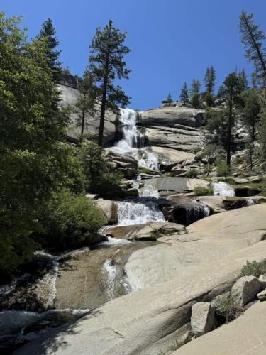 a waterfall on the side of a mountain with trees at Peppermint Falls Ranch in Ponderosa
