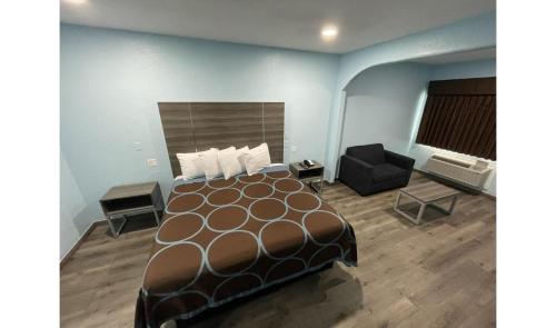a hotel room with a bed and a chair at Super Stay Inn By OYO Humble IAH East in Humble