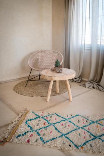 a table and a chair in a room with a rug at Blue Kaouki Boutique Hotel in Sidi Kaouki