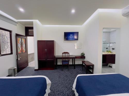 a hotel room with two beds and a desk and a table at HOTEL MARGARITA in Puebla