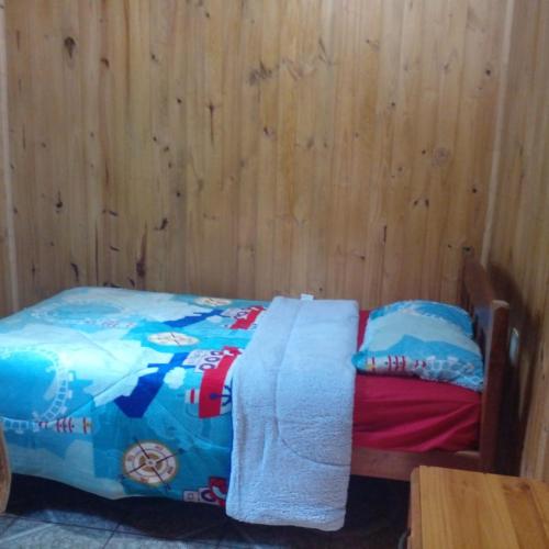 a bed in a room with a wooden wall at Refugios y Cabañas BAHIA in Puerto Iguazú