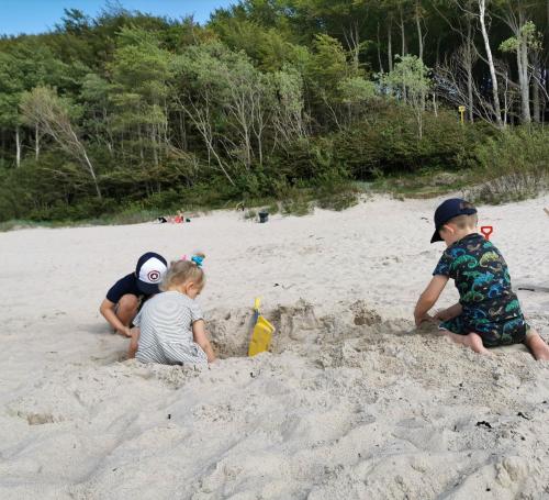three children playing in the sand on a beach at APARTAMENT 9B BLUE MARINE Poddąbie Basen Odkryty Brodziki Plac Zabaw in Poddąbie