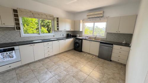a large kitchen with white cabinets and a dishwasher at Olympus Holiday villa in Pissouri