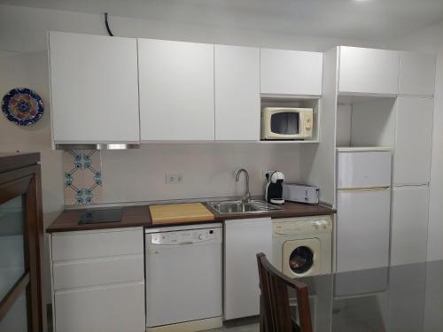 a kitchen with white cabinets and a sink and a dishwasher at El Rincón de San Fermín in Zizur Mayor