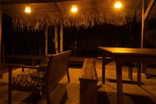 a wooden table and a chair and a table and a bench at Choupanas Awa - All inclusive em Anavilhanas in Novo Airão