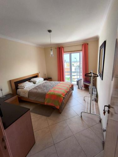a bedroom with a bed and a large window at Quarto Apartamento em Tavira in Bicas
