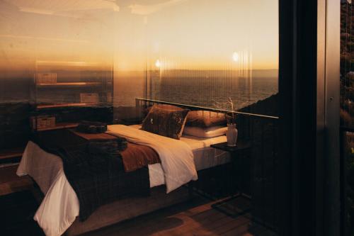a room with a bed with a view of the ocean at Klein-Hangklip in Rooiels