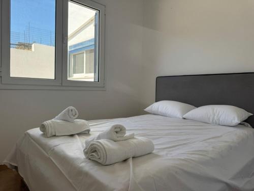 a white bed with towels on it with a window at Tinos beauty village in Kalloní