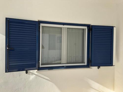 a window with blue shutters on a white wall at Tinos beauty village in Kalloní