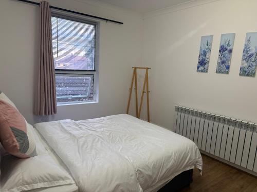 a bedroom with a white bed and a window at Wellesley Apartments in Great Clacton