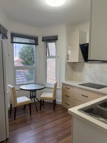 a kitchen with a table and two chairs and a table at Wellesley Apartments in Great Clacton