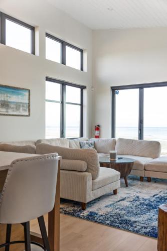 a living room with couches and tables and windows at Beachfront Villa #14 at The Beach House in Campbell River
