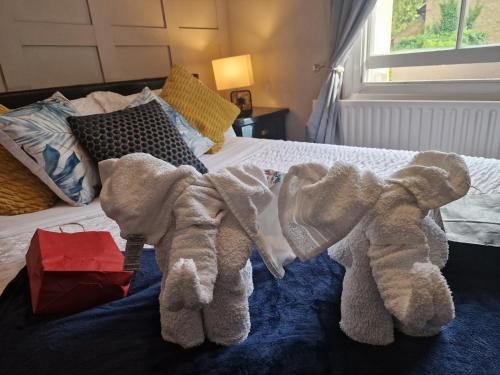 two stuffed elephants are sitting on a bed at Studio at 113b - a home away from home in Hampton Hill