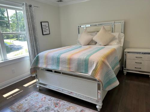 a bedroom with a bed with a colorful blanket and a window at Vacation home in Riverhead
