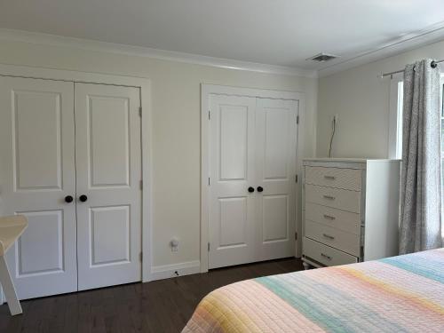 a bedroom with white doors and a bed and a dresser at Vacation home in Riverhead
