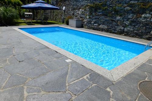 a swimming pool with a stone floor and an umbrella at Casa Panorama in Brissago