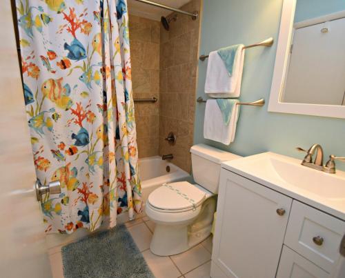 Un baño con inodoro y cortina de ducha. en Driftwood Towers, en Gulf Shores