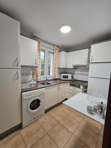a kitchen with white cabinets and a washing machine at ADOSADO FAMILIAR - PRELLEZO - Gupo RH 5 in Prellezo