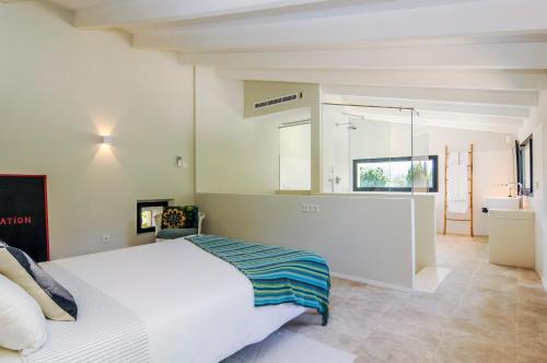 a bedroom with a white bed and a bathroom at Hort Petit de Ternelles in Pollença