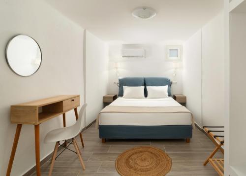 a bedroom with a bed and a desk and a mirror at DK Square in Andros