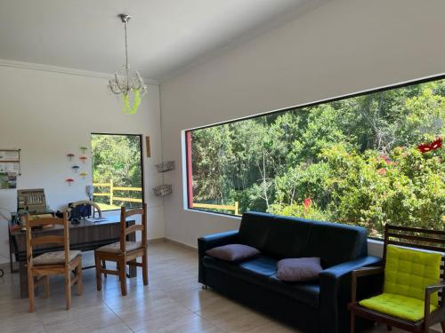 a living room with a black couch and a dining room at POUSADA PE NA TERRA EM GUARAREMA in Guararema