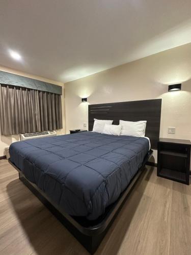 a bedroom with a large bed with a blue blanket at Del Aire Inn LAX in Inglewood