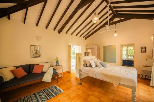 una camera da letto con un letto e un divano in una stanza di CASA SUNSHINE -Luxurious Portuguese Villa in Anjuna ad Anjuna