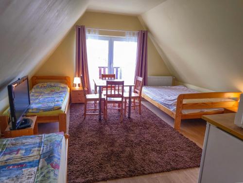 een zolderkamer met 2 bedden en een tafel en stoelen bij Pod Jesionem in Lubin