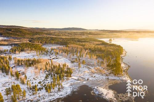 an aerial view of a lake with trees and snow at The Lazy Moose in Tällberg