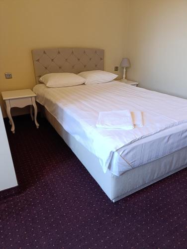 a bedroom with a large bed with white sheets and pillows at Villa Roma in Miedzierza