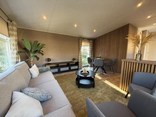 a living room with a couch and a table at Modern chalet, family oriented holiday suites near the forest and lake in Harderwijk