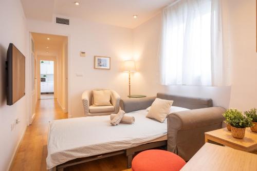 Una sala de estar con un sofá, una mesa y una silla. en Charming 2 bedroom Apartment at Virgen de Begoña, en Sevilla