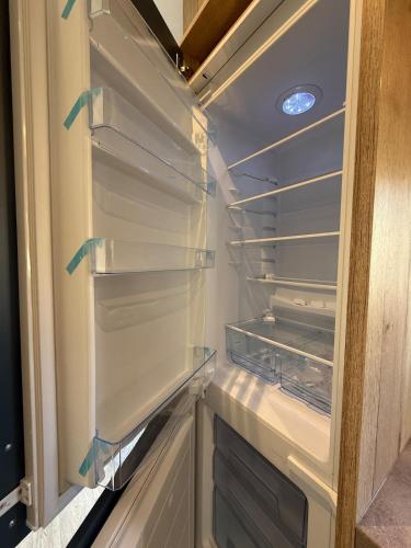 an empty refrigerator with its door open in a room at Modern chalet, family oriented holiday suites near the forest and lake in Harderwijk