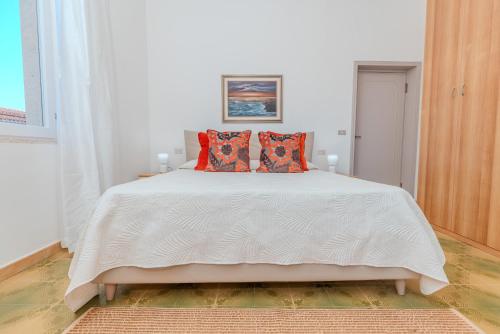 a bedroom with a white bed with orange pillows at Splendido Appartamento in centro a Padru in Padru