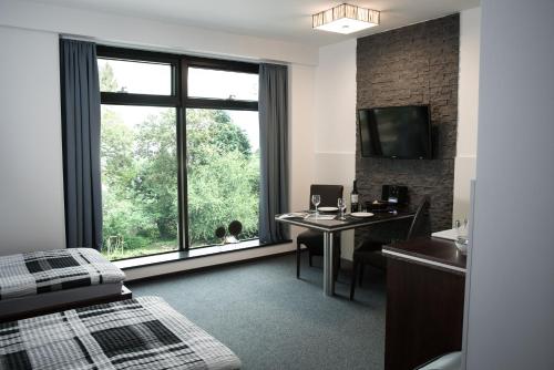 Habitación de hotel con escritorio y ventana grande. en Triumph Inn Pension, en Rangsdorf