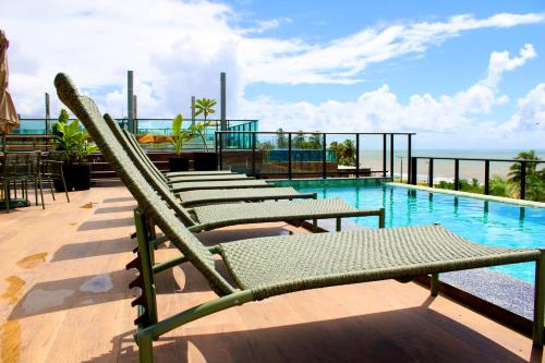 a row of lounge chairs next to a swimming pool at Jardins Almare Apart Hotel in João Pessoa