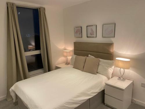1 dormitorio con 1 cama blanca con 2 lámparas y una ventana en London Penthouse Apartment with stunning views, en Moffat