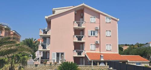 a pink building with trees in front of it at Apartment Albatross Ten in Novalja
